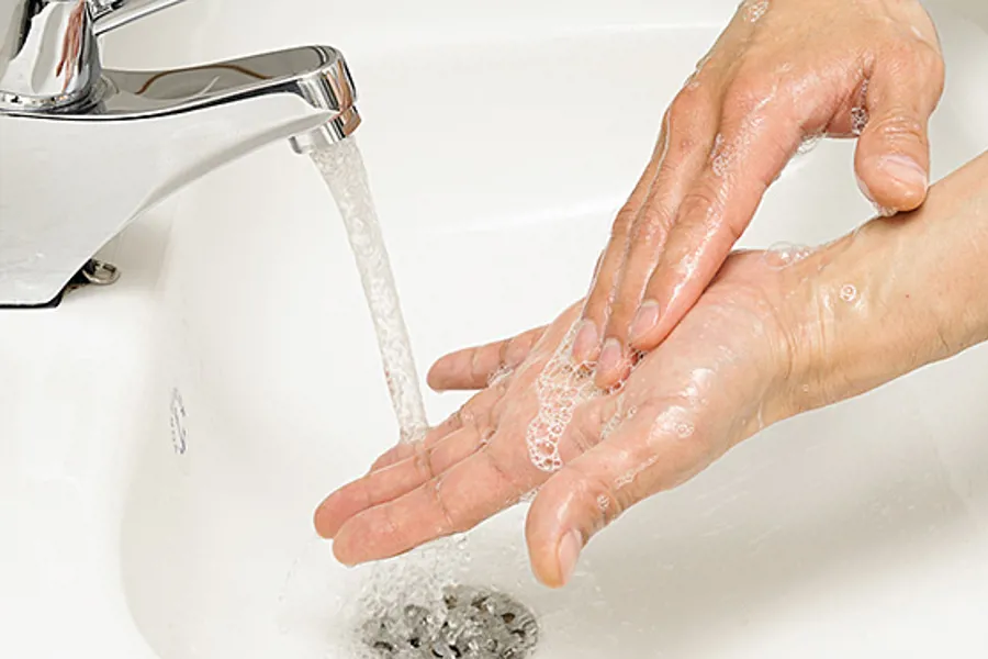 En hånd som holder en skje i en vask