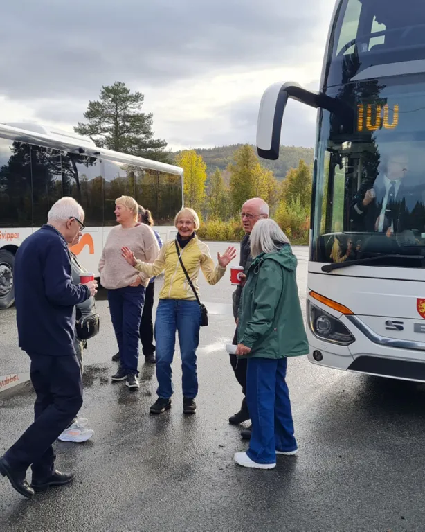 En gruppe mennesker som står ved siden av et par busser