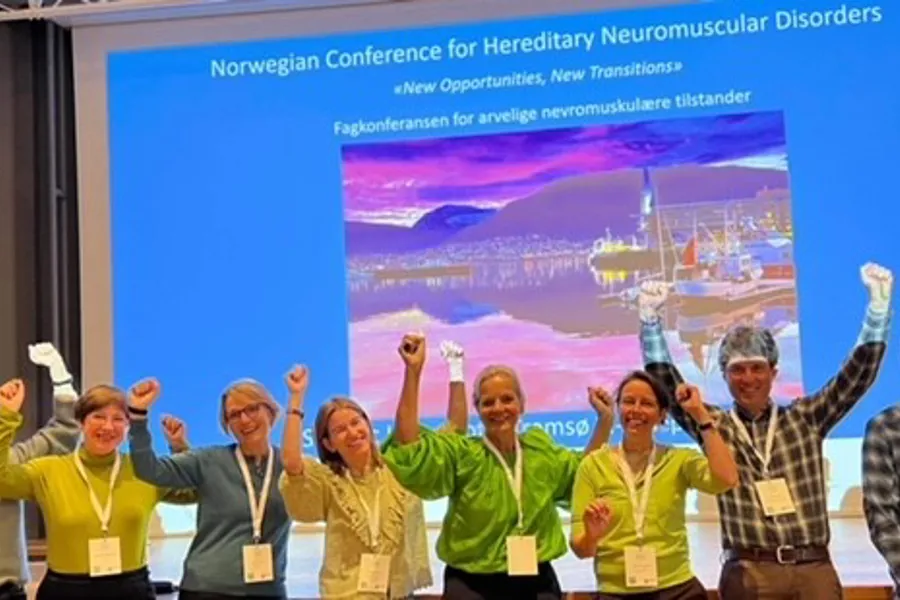 En gruppe mennesker som poserer for et bilde foran en projektorskjerm