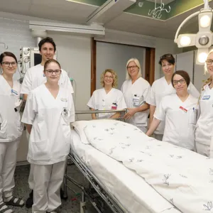 En gruppe mennesker i hvite labfrakker står ved siden av et bord