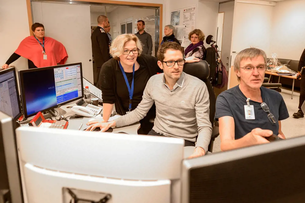 En gruppe mennesker i et rom med datamaskiner