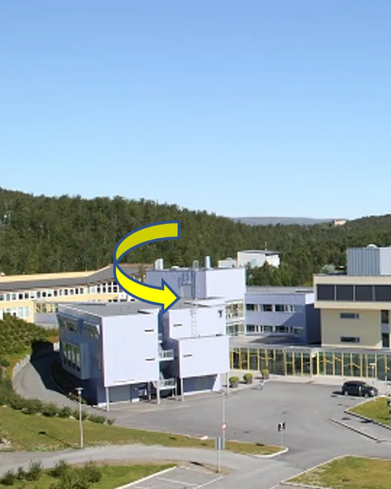 En gruppe bygninger med trær i bakgrunnen