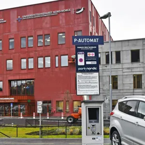 En rød bygning med parkeringsautomat foran