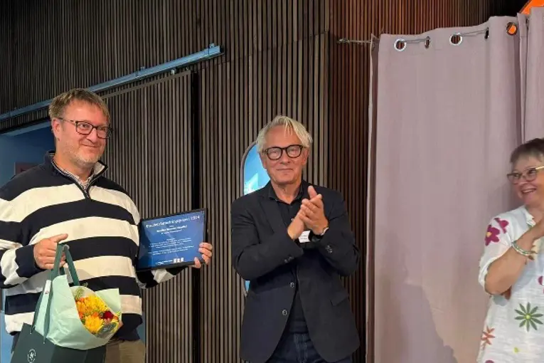 En gruppe mennesker som står foran en blå vegg